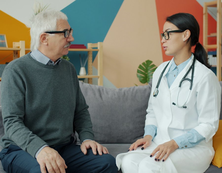 A clinician talking with an older patient on a couch